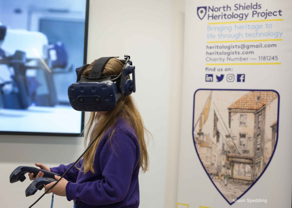 A child wearing a VR headset in front of the North Shields Heritology banner stand